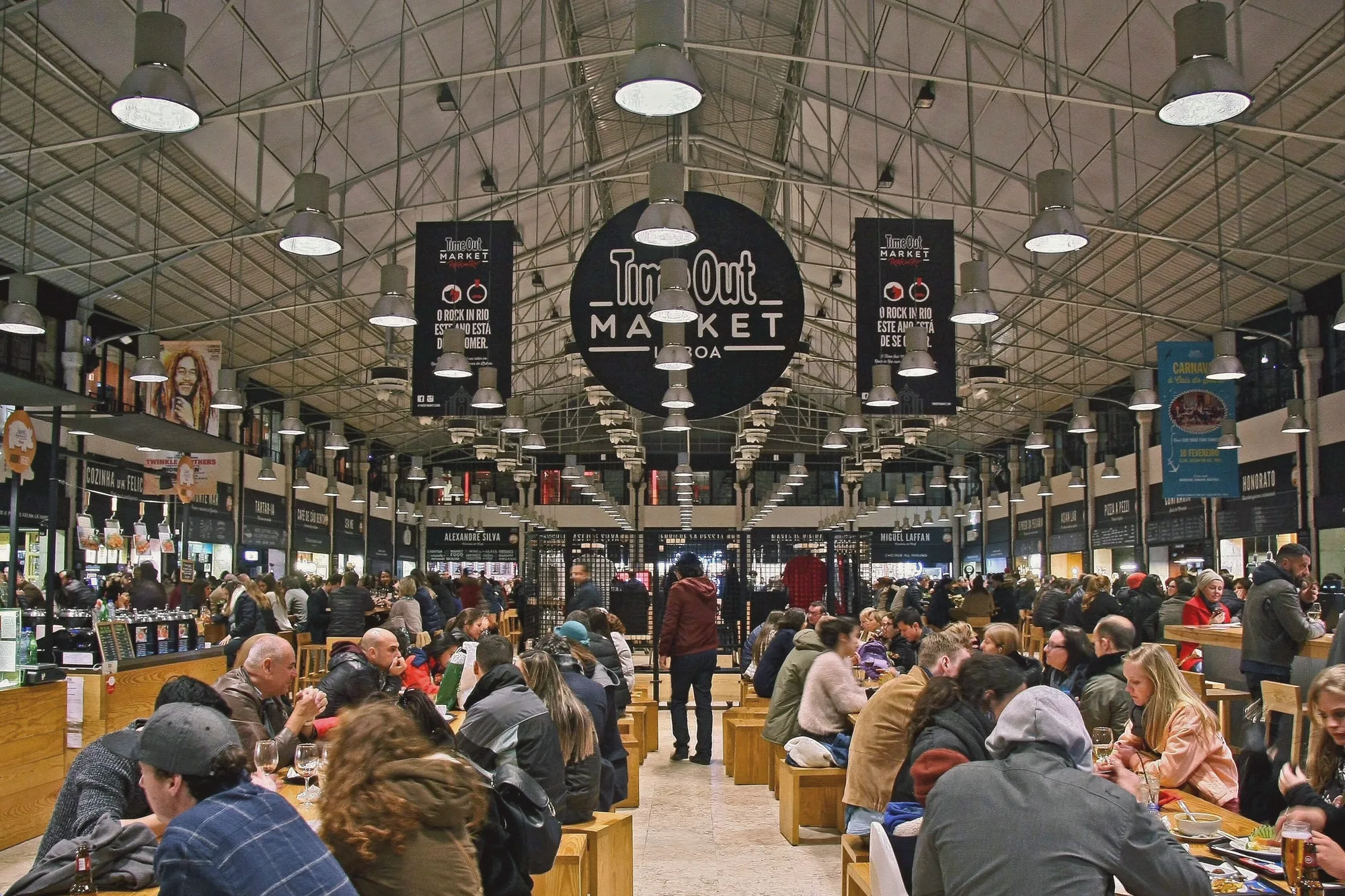 Shared tables under the iron roof of the old Mercado da Ribeira